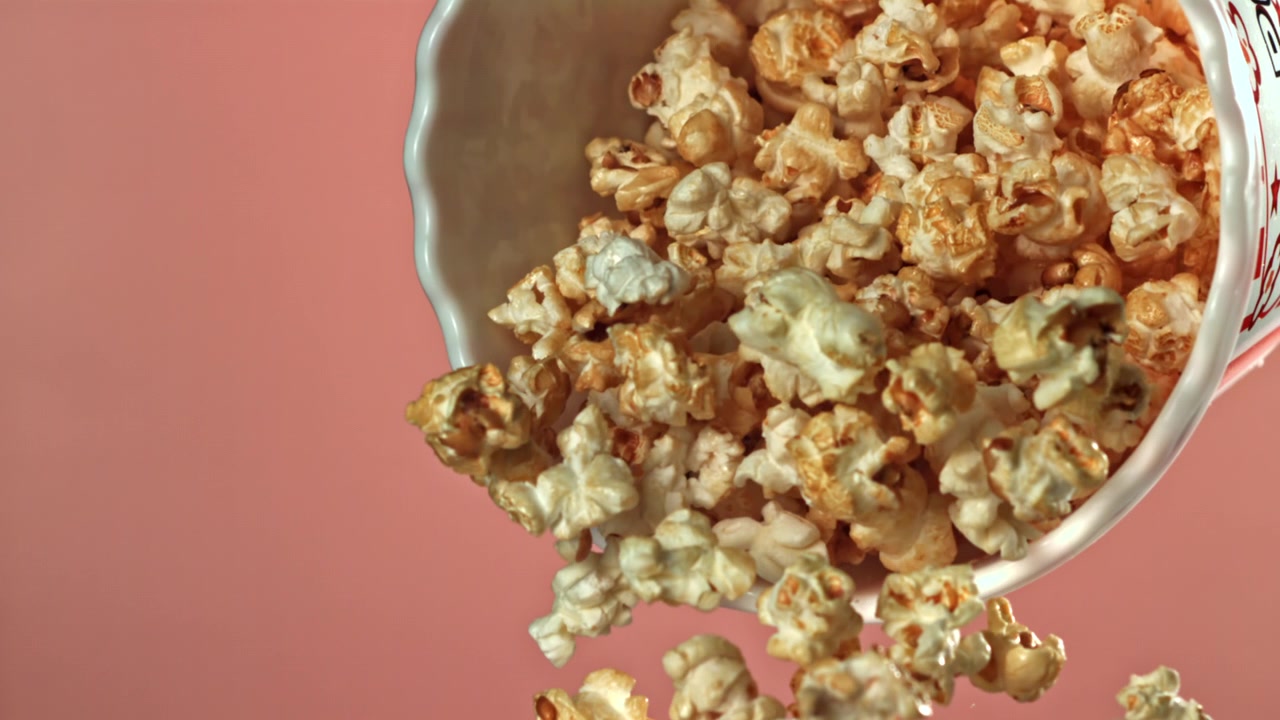 Popcorn deliziosi che cadono da un secchio a strisce al rallentatore