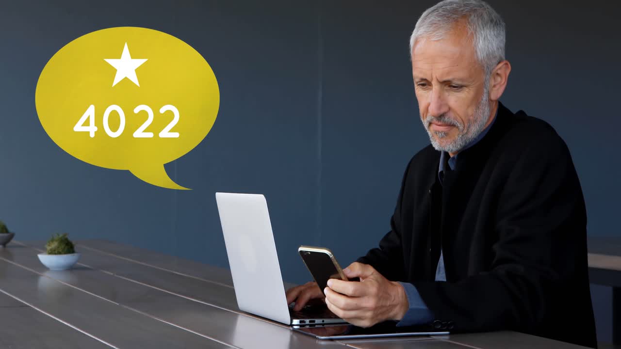 휴대폰 4k에서 브라우징하는 동안 노트북에서 일하는 남자