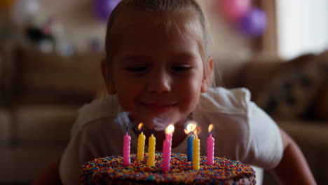 young girl blowing out birthday candles on a cake