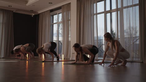 a group of women is engaged in stretching and balance with an instructor in a beautiful hall with large windows. healthy lifestyle group classes. women's sports club slow motion