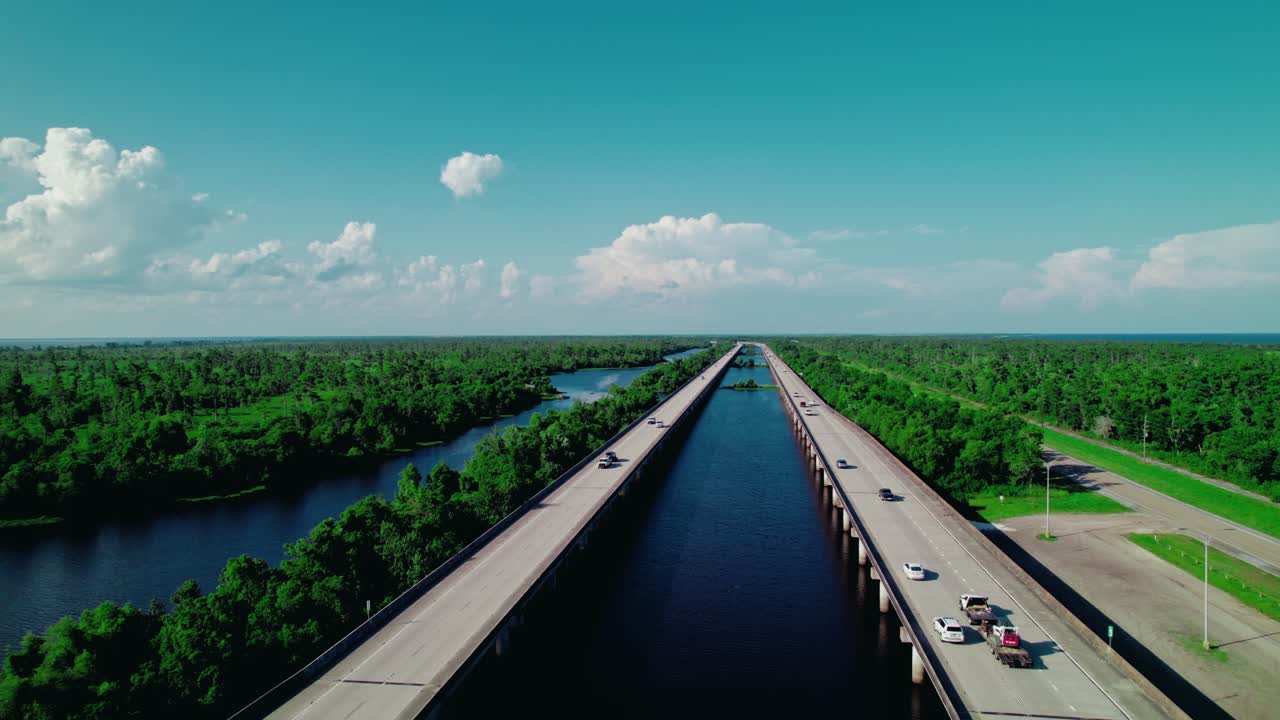 Dynamic backward aerial shot of a tow truck hauling a car along I-55 near LaPlace, Louisiana perfect for transport and roadside service projects.