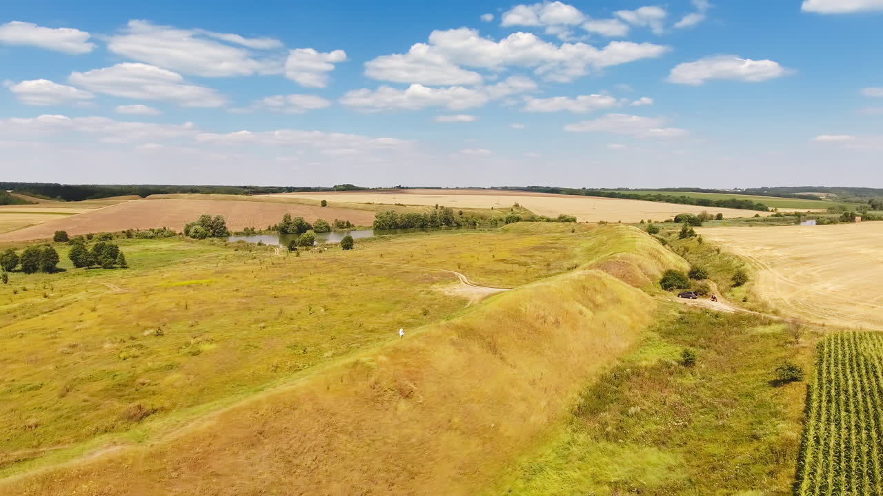 Diverse landscape including woods, meadows, pond, hills and farmlands. Girl walking by the path on top of the hill. Sunny day nature concept.