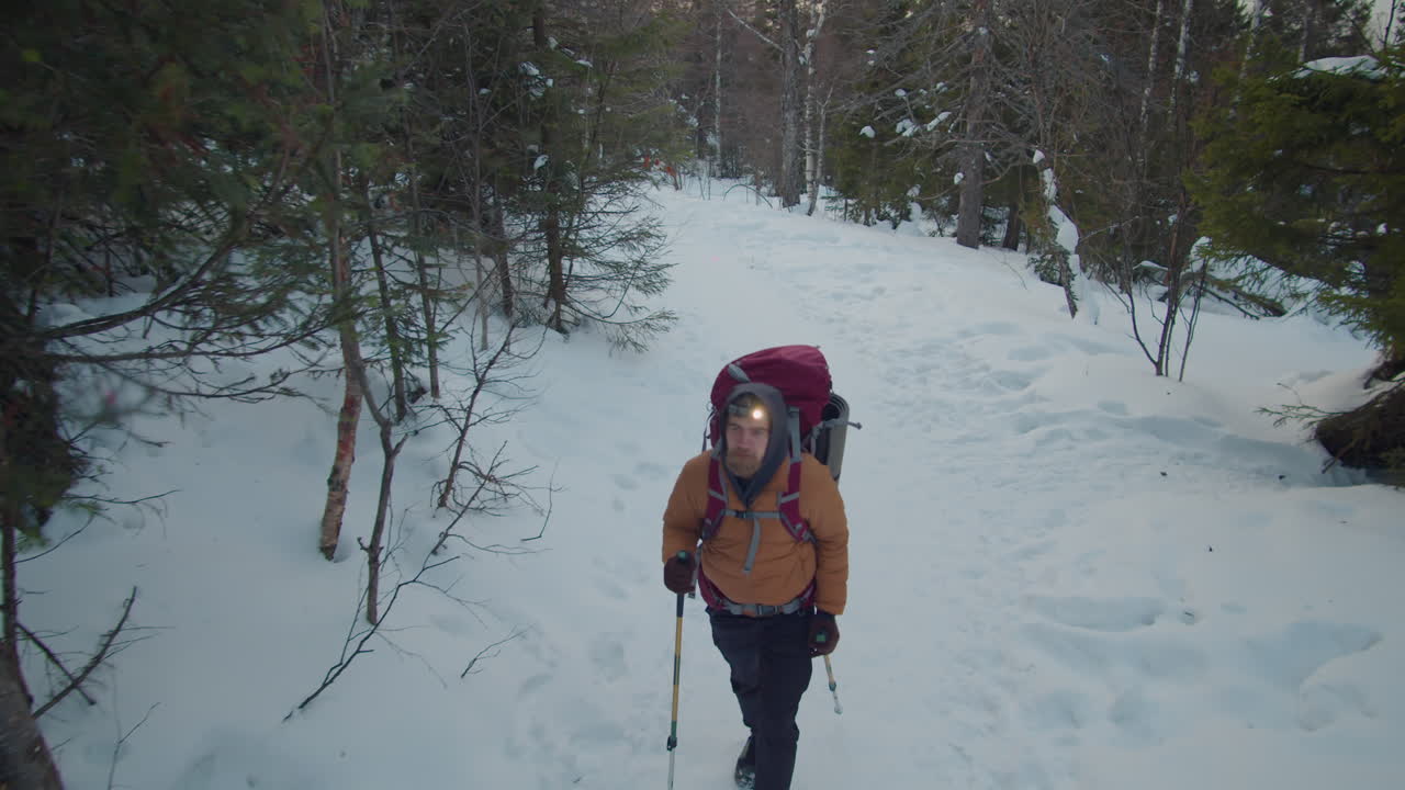 Hiker with Headlamp and Sticks Walking on Snowy Trail