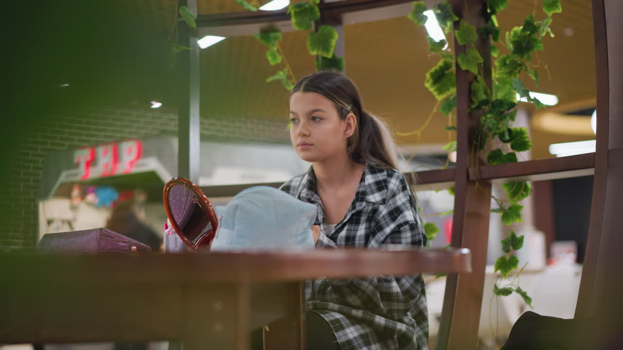 젊은 여성은 테이블에 앉아서 을 사용하여 이마에 메이크업을 부드럽게 뿌리며, 화장품이 테이블에서 보이는 편안한 실내 환경에서 흐릿한 배경을 가지고 있습니다.