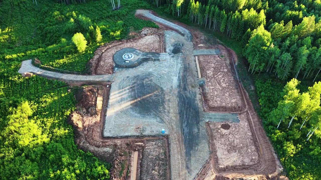 Expansive construction site for a wind turbine foundation being prepared in a dense forest
