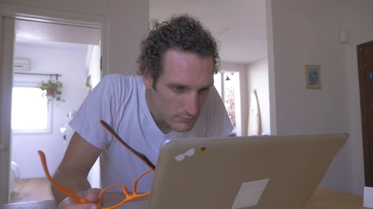 Man working on a computer at home having difficulties to see