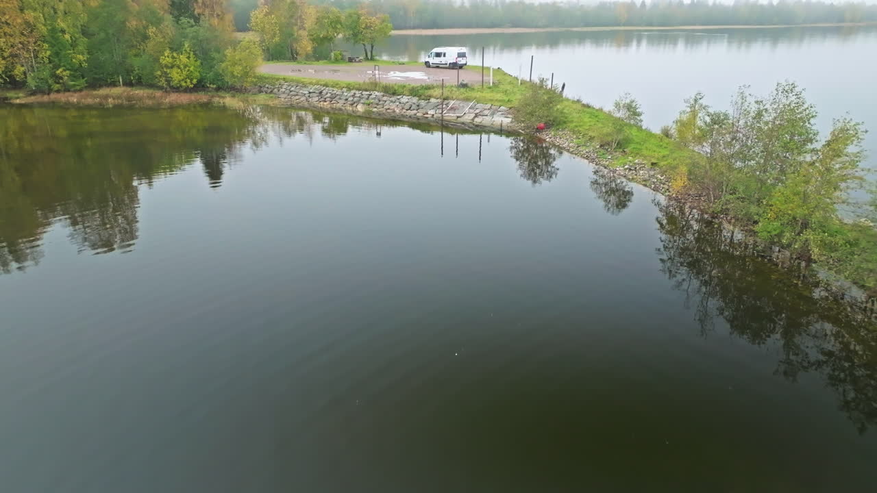 스웨덴의 안개가 많은 아침에 거울 반사와 함께 작은 섬 위에 주차 된 밴