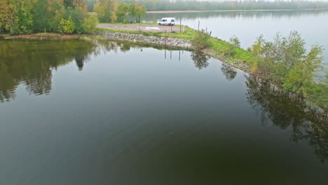 van parked over small island with mirror reflections during foggy morning in sweden