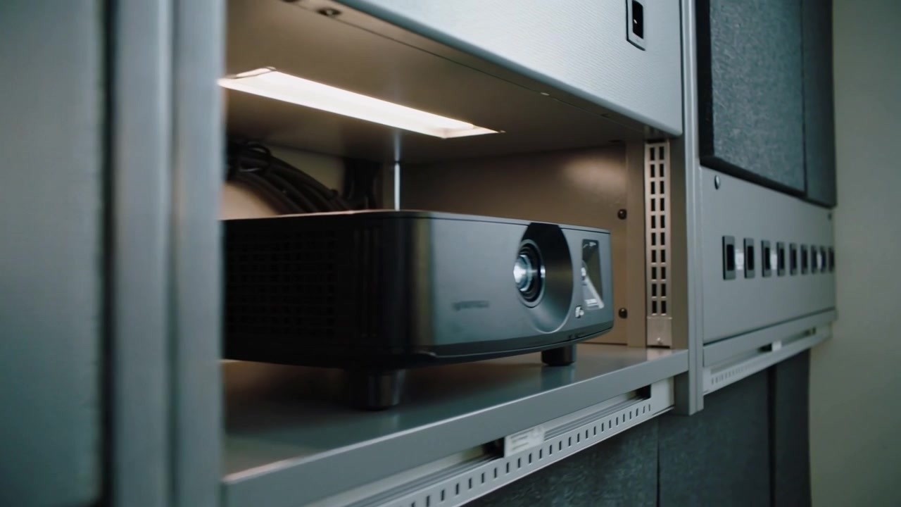 Bewegende camera terwijl plankverlichting aangaat, onthult zwarte projector op AV-rek, met tekstruimte