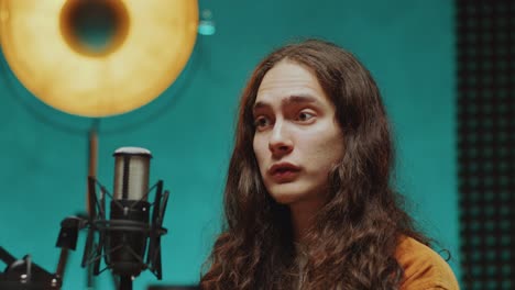 young podcast guest speaking in mic as recording interview in studio