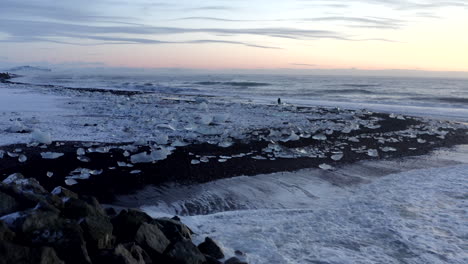 Antena:-Olas-Rompiendo-En-Rocas-En-La-Playa-Negra,-Diamante-En-Islandia-En-Invierno-Nieve,-Hielo,-Olas,-Agua