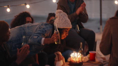 feliz grupo de amigos celebrando fiesta de cumpleaños en la azotea al atardecer hermosa joven soplando velas disfrutando de la celebración haciendo un brindis a la amistad