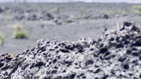 Cinematic-booming-up-shot-from-foreground-lava-rock-to-reveal-volcanic-landscape-at-the-crater's-edge-of-Kilauea-caldera-in-Hawai'i-Volcanoes-National-Park