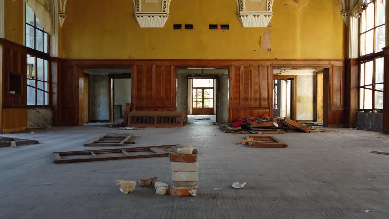 Main hall of Tskaltubo spa with empty chairs, peeling paint, and high ceilings in warm light