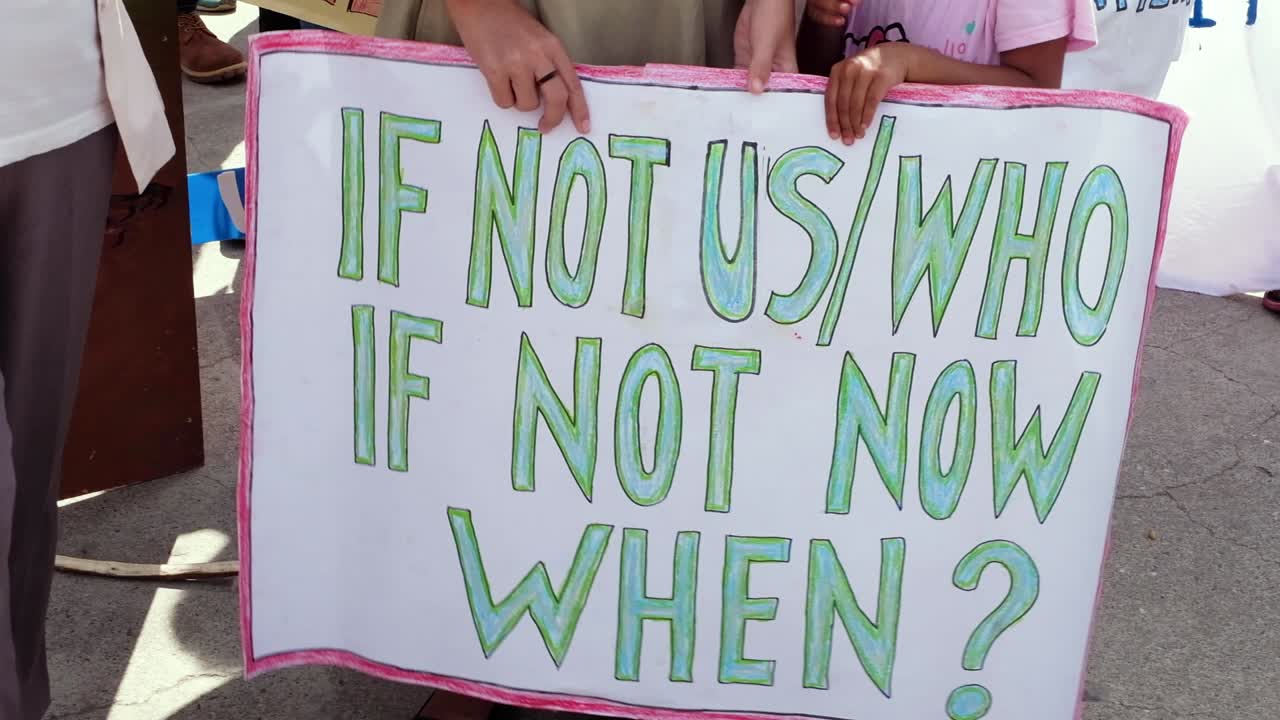 People gathering, marching and closeup of environment climate change hand drawn sign. Climate change march in capital Dili, Timor Leste, Southeast Asia.