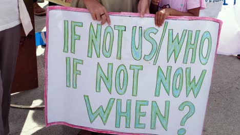 people gathering, marching and closeup of environment climate change hand drawn sign. climate change march in capital dili, timor leste, southeast asia.