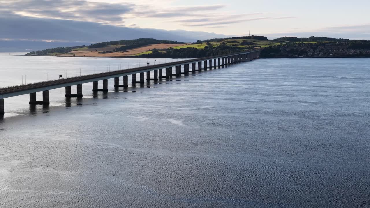 Drone pulls back from Tay Road Bridge, revealing river, distant hills, and soft daylight