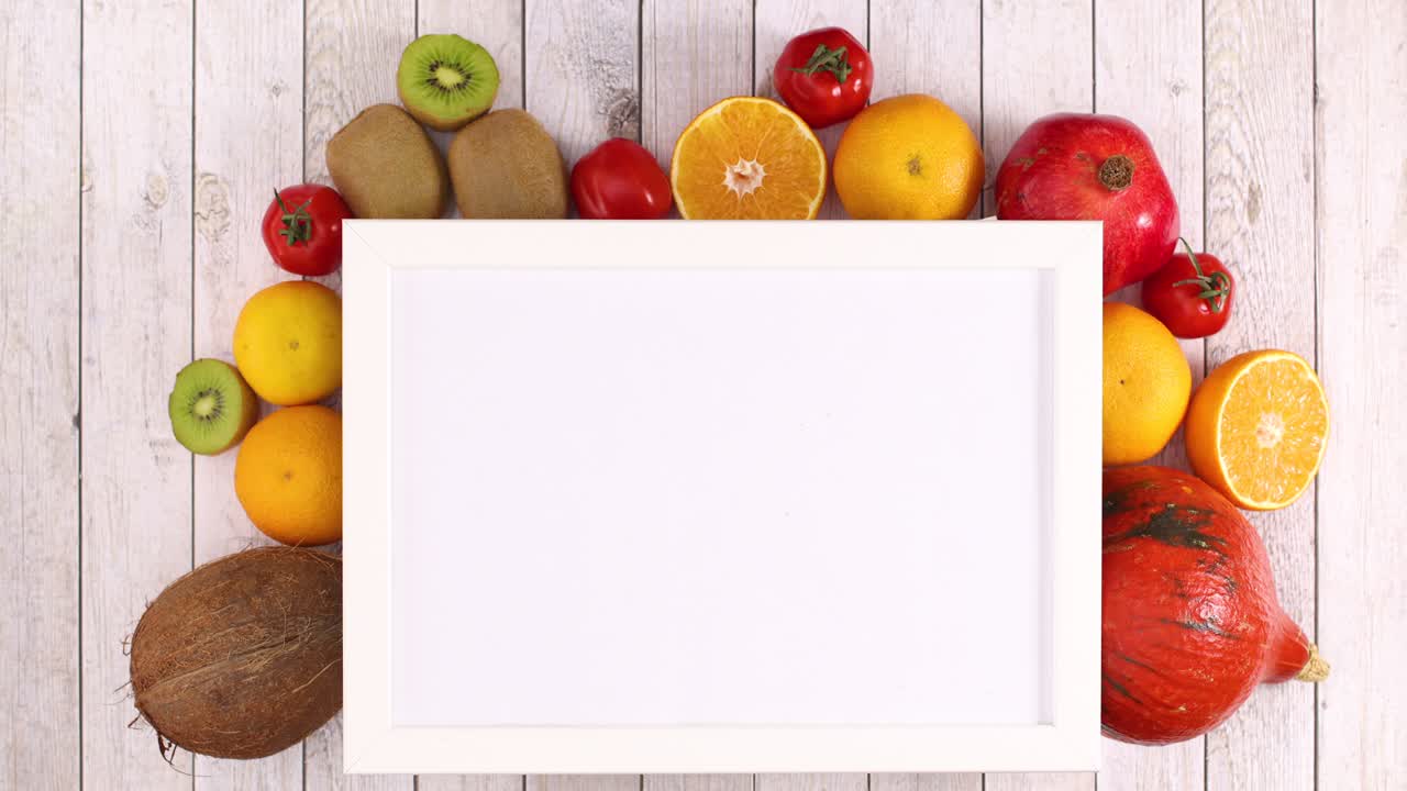 White frame with place for text and moving fruits and vegetables under frame. Stop motion