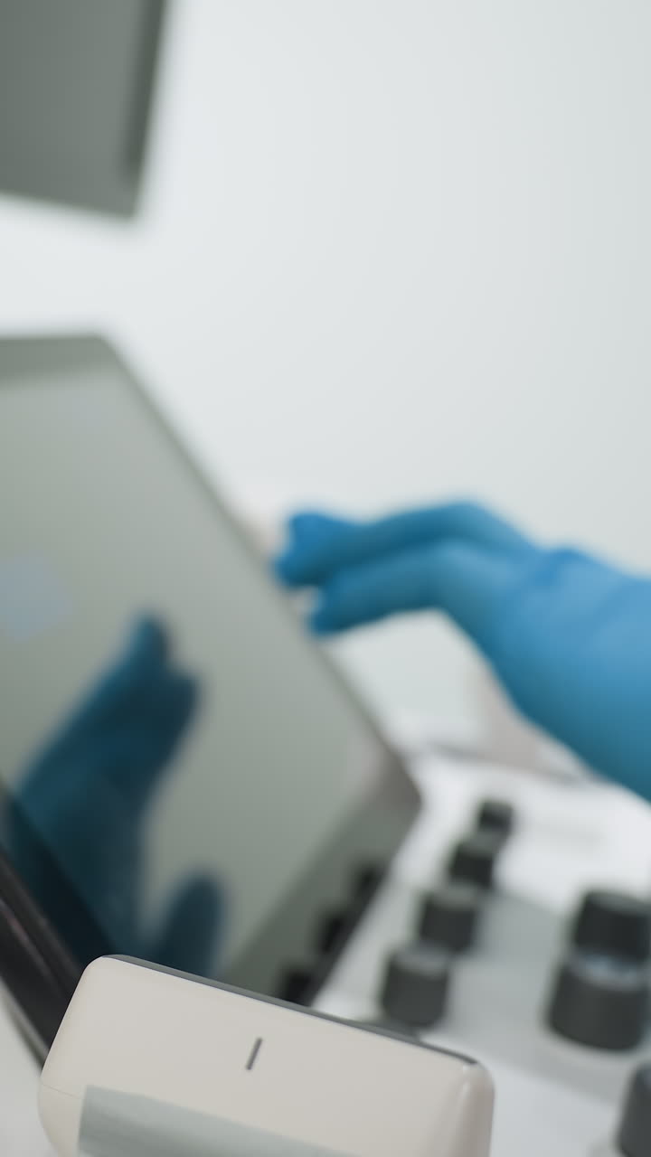 Consola de ultrasonidos con pantalla táctil utilizada por un técnico con guantes; primer plano del monitor y los controles mientras el ecografista ajusta los parámetros y los modos para una captura de imágenes óptima en una sala de imagenología clínica