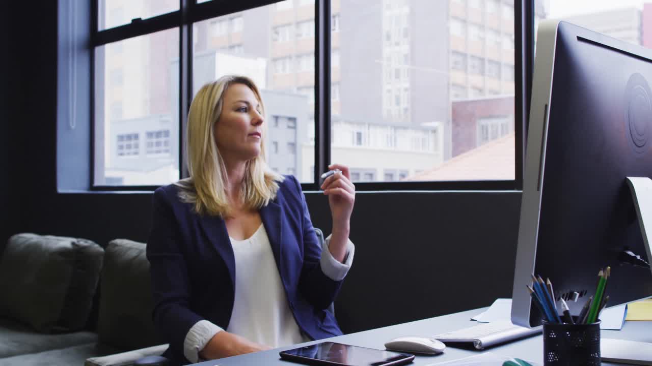 donna d'affari caucasica seduta a una scrivania usando un computer in un ufficio moderno