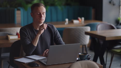 smiling man with works from home in his kitchen using a laptop. remote work and remote learning. remote work during self-isolation in quarantine man works with financial documents.