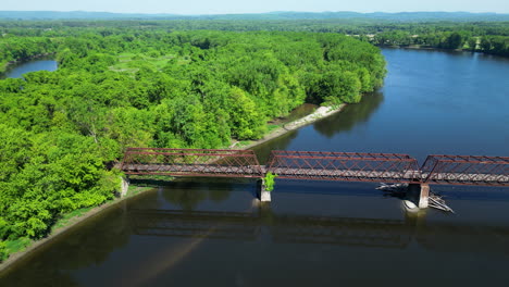 Aerial-lateral-shot-of-bridge-over-Connecticut-River-and-green-forest-landscape