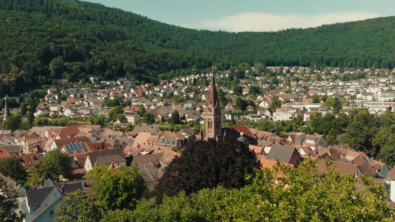 Aerial wide angle sliding establishing view of Odenwald cityscape with trees in the foreground