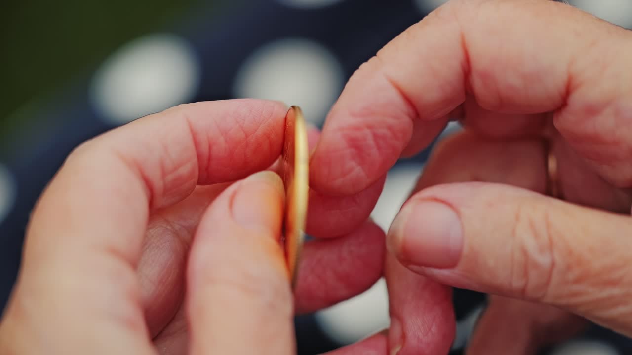 Close up of elderly woman inspecting gold Bitcoin coin under natural daylight