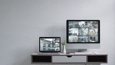 wall mounted computer monitor and laptop on desk with security camera views on screens, slow motion