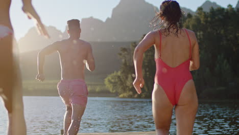 teenage-friends-running-jumping-off-jetty-in-lake-at-sunset-having-fun-splashing-in-water-enjoying-freedom-sharing-summer-adventure-on-vacation