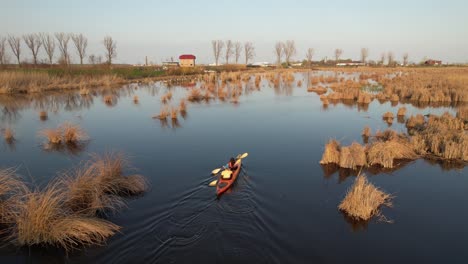 kayaker paddling through a tranquil marshland at sunset