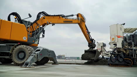 excavator dumping wet cement for a concrete paving machine building a road