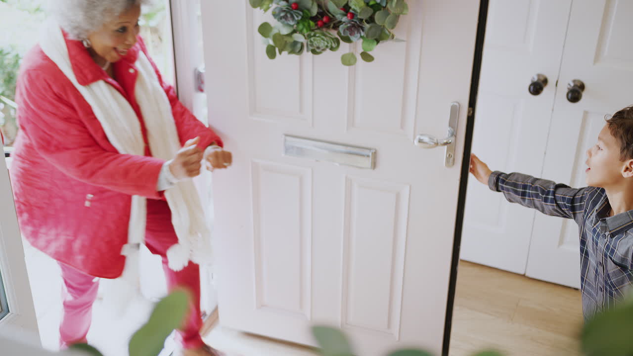 흥분 된 손자 들 은 크리스마스 날 에 방문 하는 할아버지 할머니 들 에게 선물 을 선물 하고 인사 한다