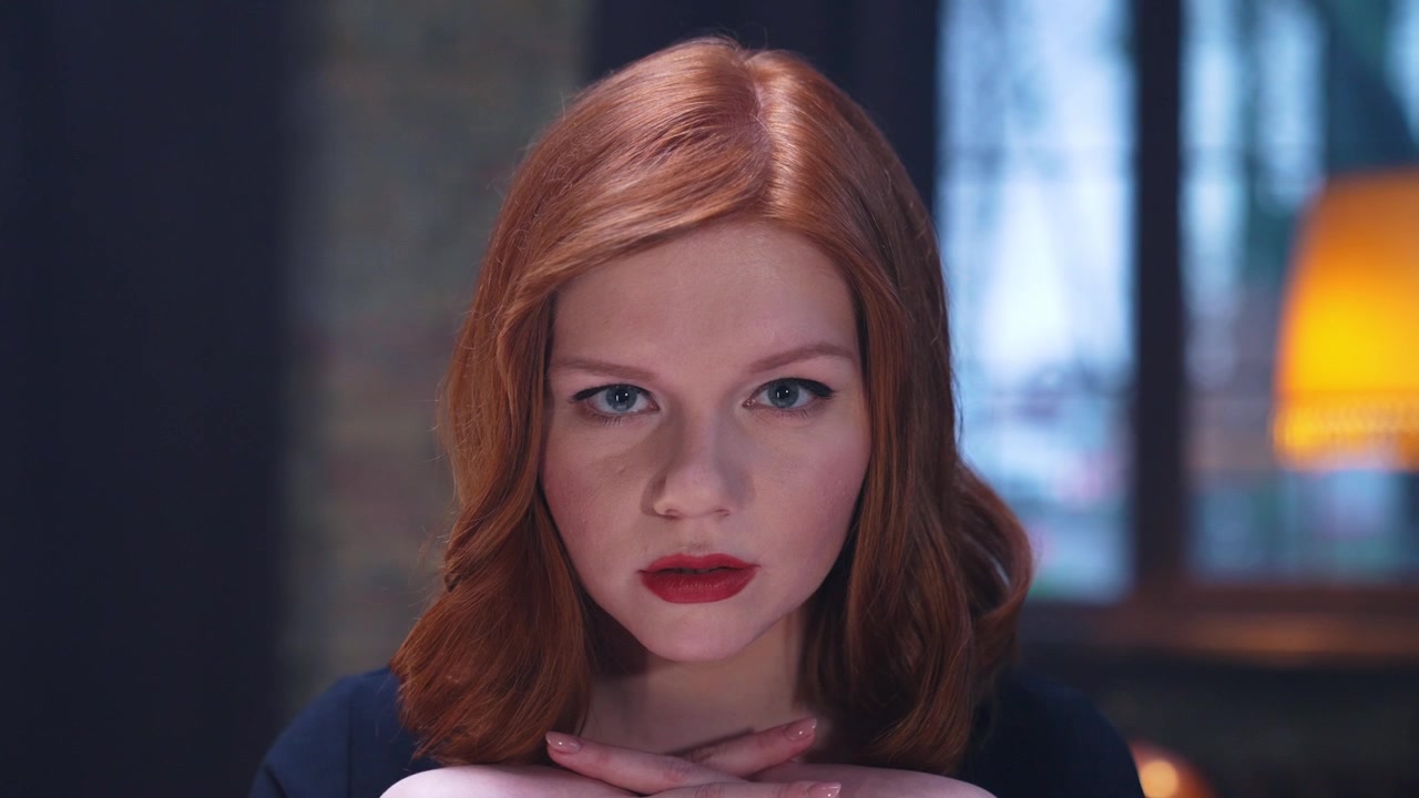 Young Red-Haired Woman with Serious Expression Looking at Camera
