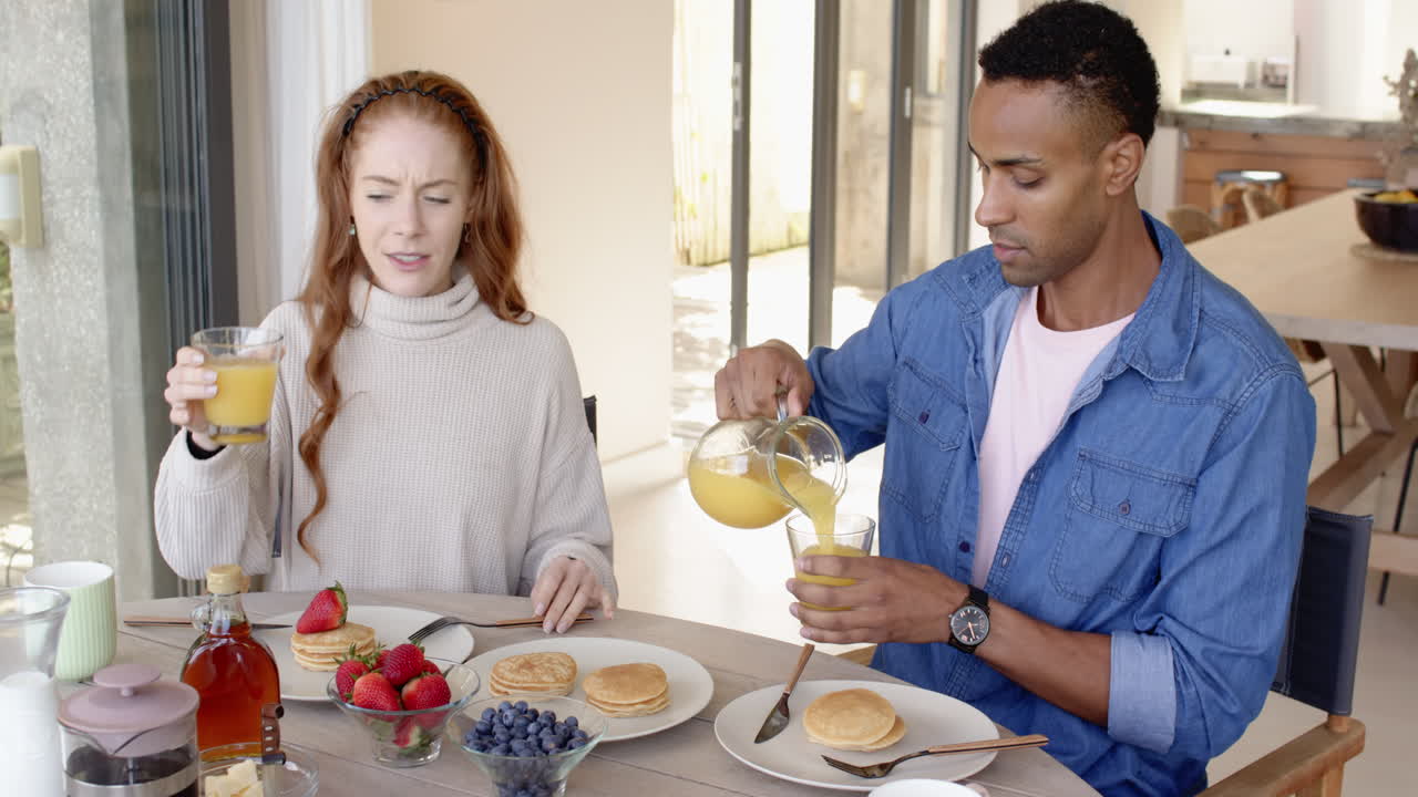 Couple enjoying breakfast with pancakes and orange juice at home