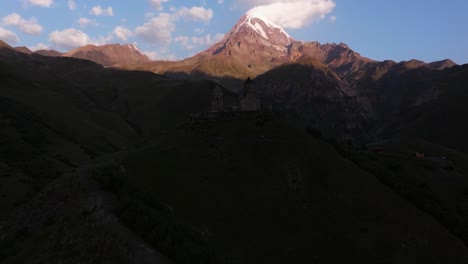 aerial boom shot above gergeti trinity church, georgia at sunrise