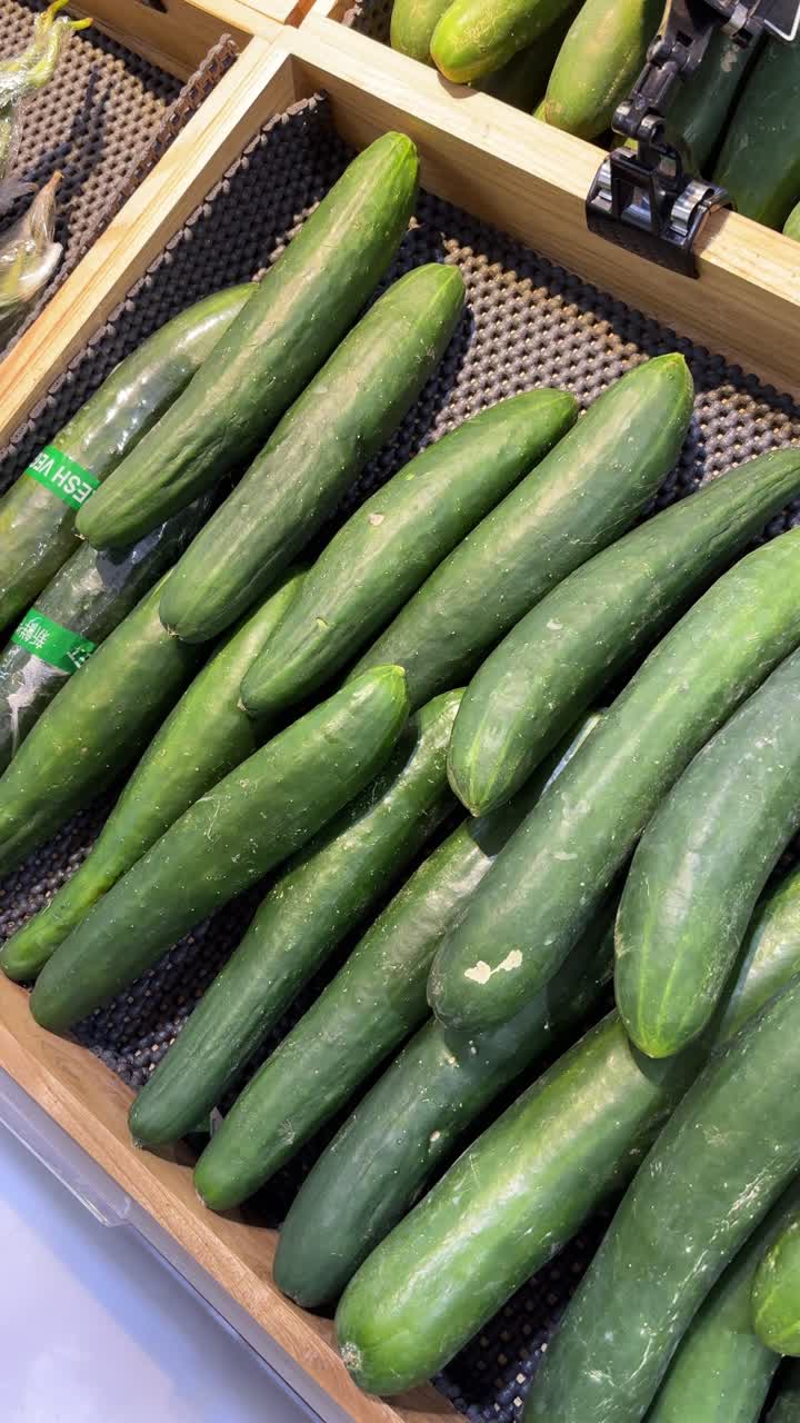 Fresh Green Cucumbers Displayed in a Wooden Crate at a Grocery Store