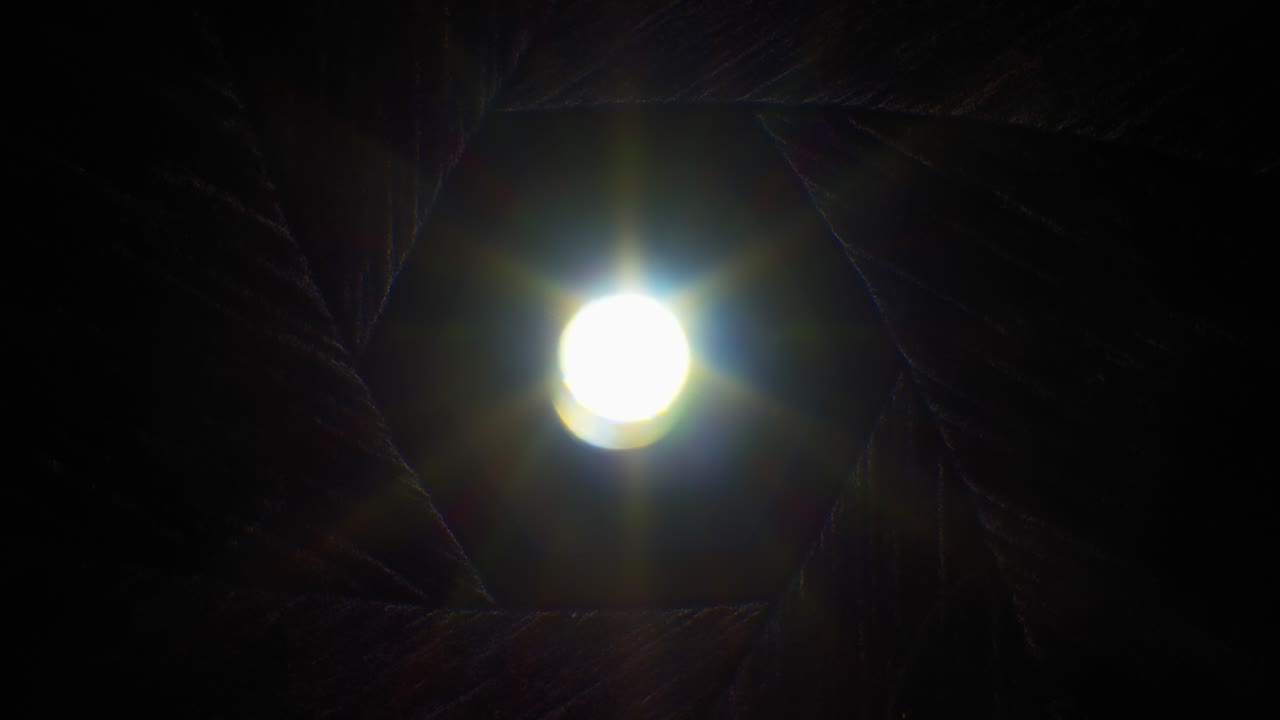 Diaphragm blades opening fast with sun rays shining through old camera lens, fade out to white