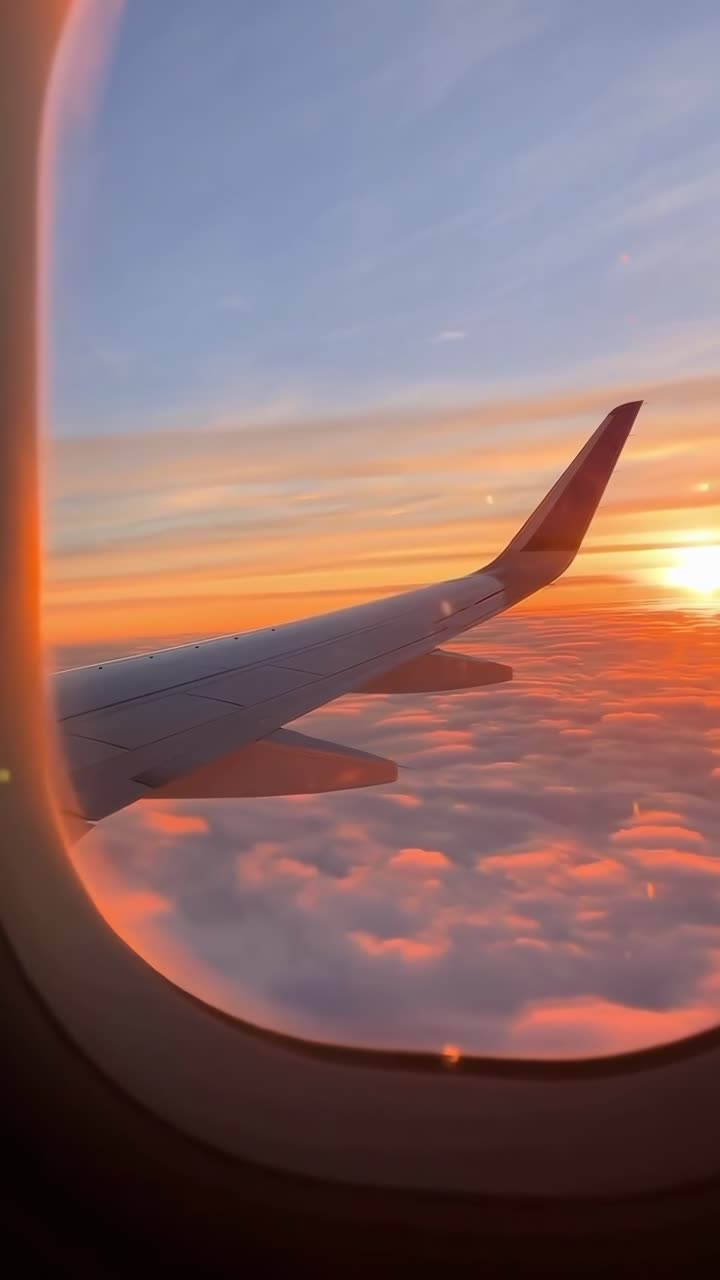 Vista video aerea da un finestrino dell'aereo, che cattura un tramonto sulle nuvole con colori vivaci