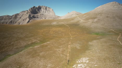 toma aérea de cuatro personas caminando por un sendero hacia la montaña olympus en un día soleado de verano