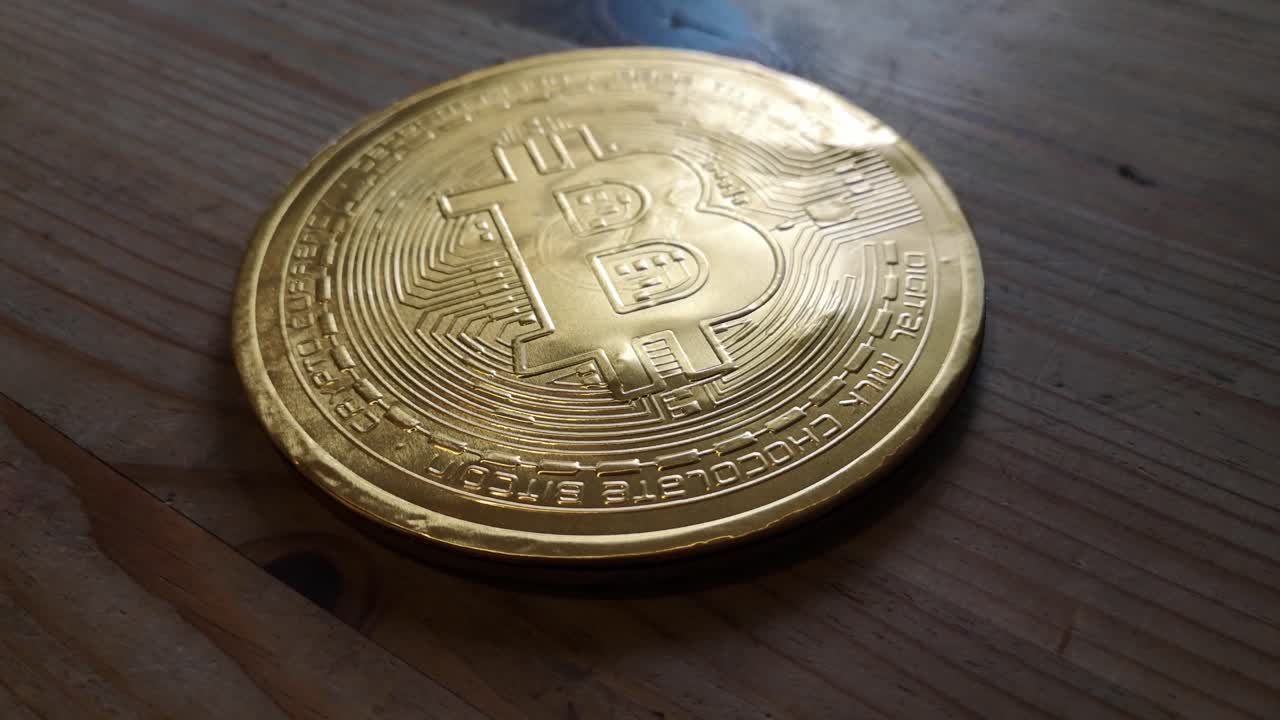 concepto de moneda criptográfica de bitcoin de oro de chocolate envuelto en la órbita de la mesa de la cocina de madera hacia adelante a la derecha