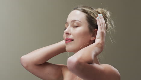 portrait of smiling caucasian woman with eyes closed touching her hair, copy space, slow motion