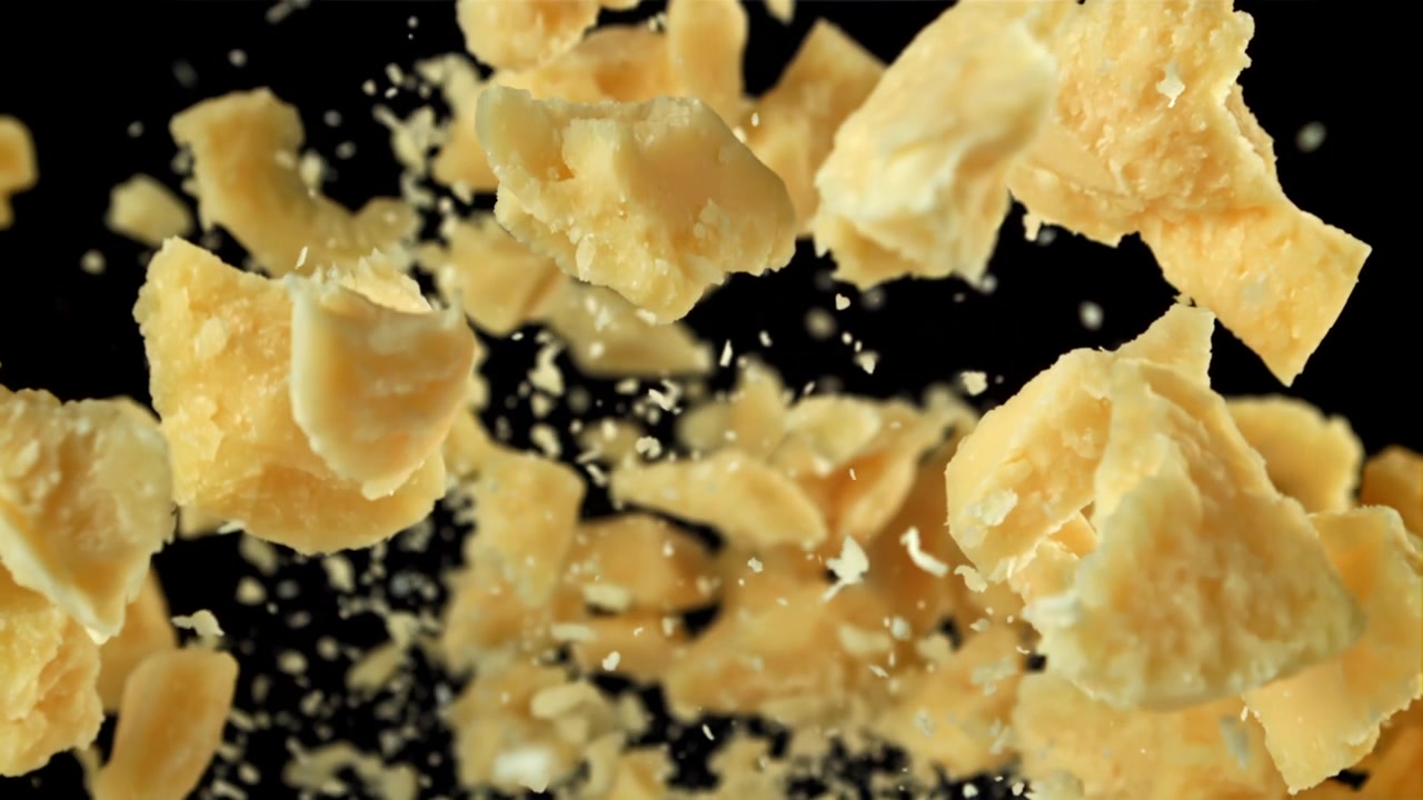 Pezzi di Parmigiano in caduta al rallentatore su sfondo nero