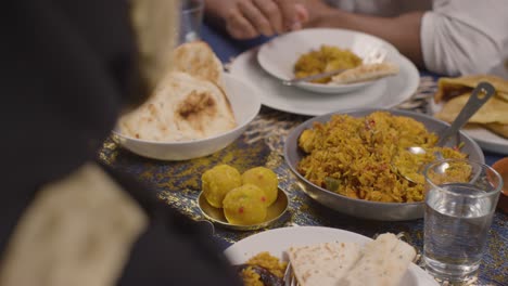 close up of muslim muslim family sitting around table at home eating meal to celebrate eid 1