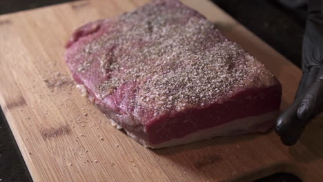 Chef-wearing-food-gloves-prepping-beef-brisket-to-be-smoked