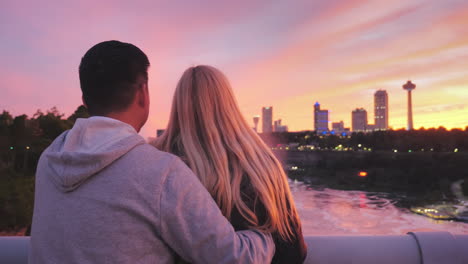 pareja multiétnica parada en un puente entre estados unidos y canadá admirando una hermosa puesta de sol