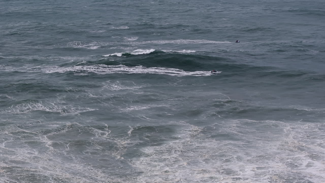 Jet ski crews in rough Nazaré surf, aerial ocean drone shot. Portugal, Europe
