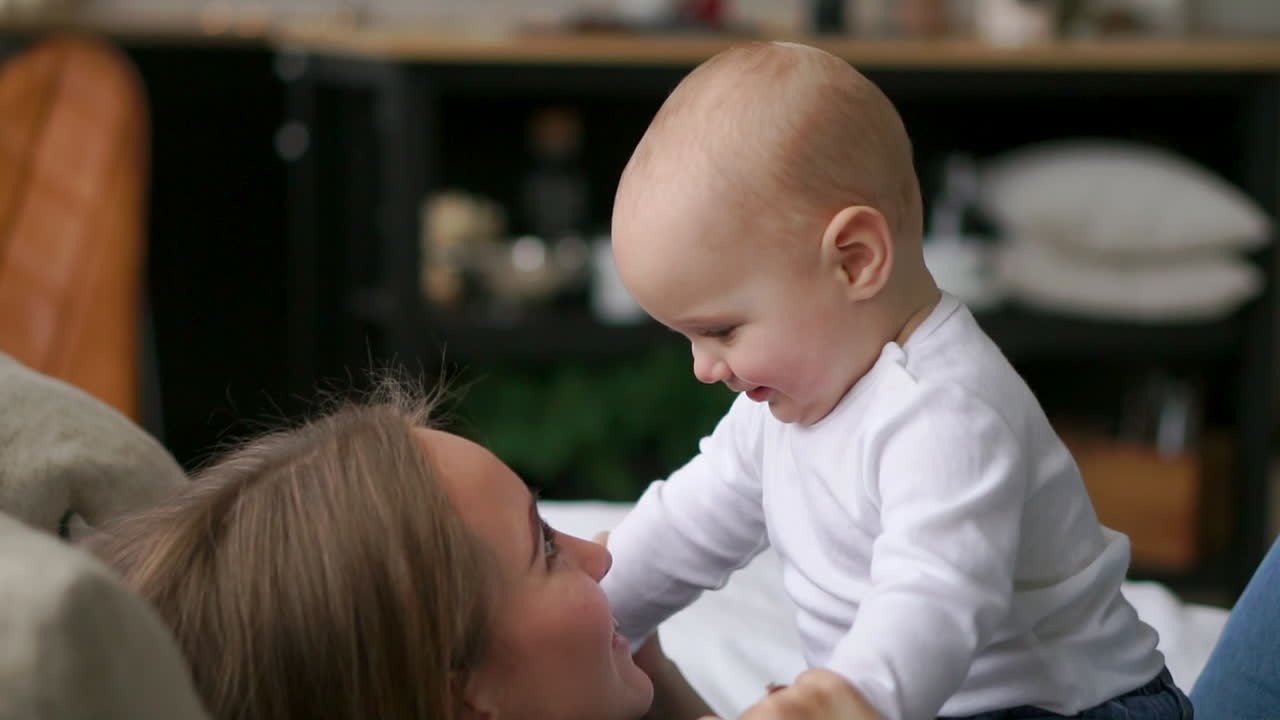 어린 엄마 는 침대 에서 아기 소년 과 함께 놀고 있다