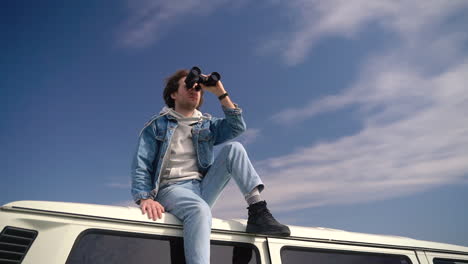 young boy looks around with a pair of binoculars on the roof of a caravan 3