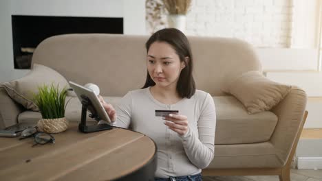 happy young women doing payments online or shopping in internet store holding credit card using tablet pc.